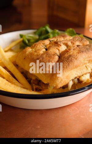 Gegrillte Focaccia-brot Sandwich mit geschmolzenem Käse Wurst gefüllt, serviert mit Pommes Frites und Salat Stockfoto