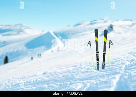 Skier und Stöcke in den Schnee festgesteckt. Skipiste im Hintergrund. Konzept des alpinen Skilaufs und sportlich Aktive Stockfoto