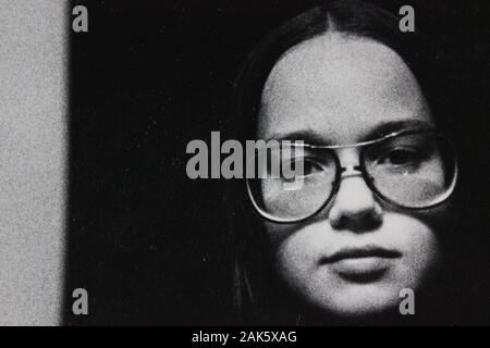 Feine Schwarzweißfotografie der 1970er Jahre einer Frau, die eine Brille trägt und die Kamera betrachtet Stockfoto
