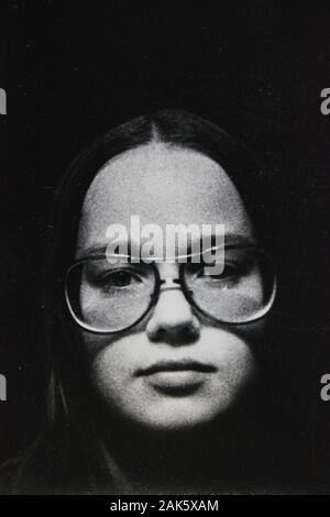 Feine Schwarzweißfotografie der 1970er Jahre einer Frau, die eine Brille trägt und die Kamera betrachtet Stockfoto