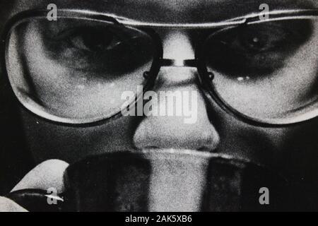 Feine Schwarzweißfotografie der 1970er Jahre einer Frau, die eine Brille trägt und die Kamera betrachtet Stockfoto