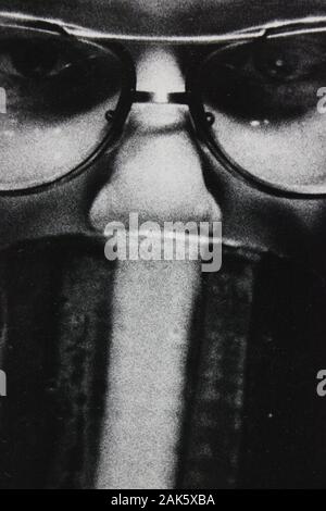 Feine Schwarzweißfotografie der 1970er Jahre einer Frau, die eine Brille trägt und die Kamera betrachtet Stockfoto