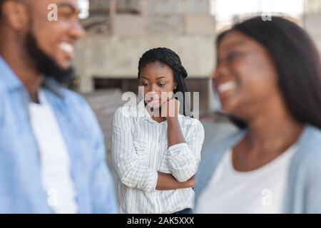 Drittes Rad. Verärgert schwarze Mädchen eifersüchtig zu ihr dating Freunde, allein auf den Hintergrund im Freien, selektiven Fokus Stockfoto