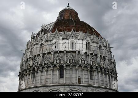 Pisa, Italien. Detail der Kuppel von Pisas Baptisterium mit der Statue des heiligen Johannes, die darauf zu sehen ist. Regnerischer Tag mit dunkel bewölktem Himmel. Stockfoto