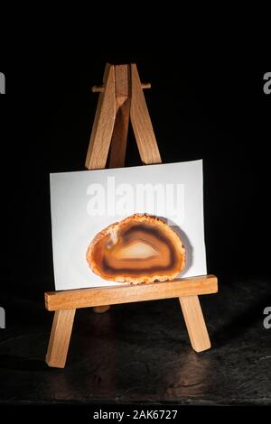 Studio Aufnahme einer rund, dünn und poliert Achat Scheibe vor Licht auf eine Miniatur Staffelei stand vor der weißen Karton. Stockfoto