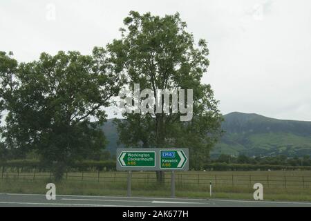 Beschilderung nach Workington Cockermouth Keswick M6 Lake District Cumbria UK Camping Camp Beschilderung M6 Pfeilpfeile Straße Zaun Metall Zäune Hügel Berg Stockfoto