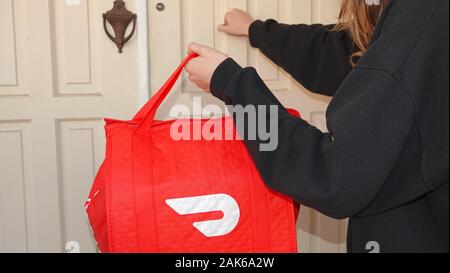 Person Klopfen an einer Tür, eine DoorDash Lieferung. Stockfoto