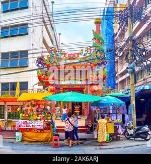 BANGKOK, THAILAND - 15 April 2019: der Straße essen Karren vor der kleinen Chao Por Khao Tok chinesische Schrein mit malerischer Gates ist sandwiched zwisch Stockfoto