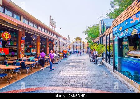 BANGKOK, THAILAND - 15 April, 2019: Die lange Straße mit offenen Restaurants auf beiden Seiten und die Kellner einladenden Kunden, am 15. April in Bangkok. Stockfoto