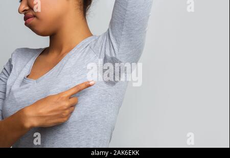 Der junge schwarze Frau an den verschwitzten Shirt suchen 7/8, grauen Hintergrund, Kopieren, nasse Achselhöhle problem Stockfoto