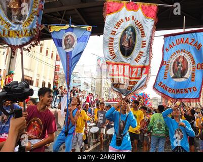 Schwarzen Nazareners devotees halten Fahnen und Banner während der Prozession. Hunderte von Schwarzen Nazareners devotees um das Land der Prozession und der Segen der Replikate durch die Straßen der Quiapo in Manila. Es zeigt die Filipinos tiefen Glauben und die Verehrung des Schwarzen Nazareners. Stockfoto