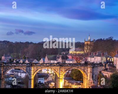 Flutlicht Eisenbahnviadukt über den Fluss Nidd und St Johns Kirche in der Dämmerung aus dem Schlosspark in Knaresborough Yorkshire England Stockfoto