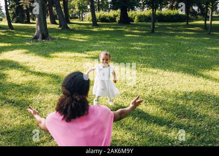 Gerne kleine Mädchen in den Arm der Mutter im Park läuft Stockfoto