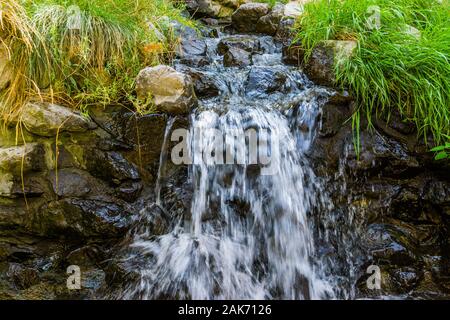 Kleine streaming Wasserfall, Wasser fließt über Felsen, schöne Natur Hintergrund Stockfoto