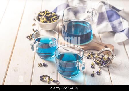 Blauer Tee in Glas-Tassen und Glas Teekanne, weißem Holz Hintergrund Stockfoto