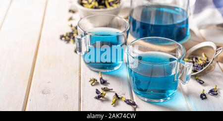 Blauer Tee in Glas-Tassen und Glas Teekanne, weißem Holz Hintergrund Stockfoto