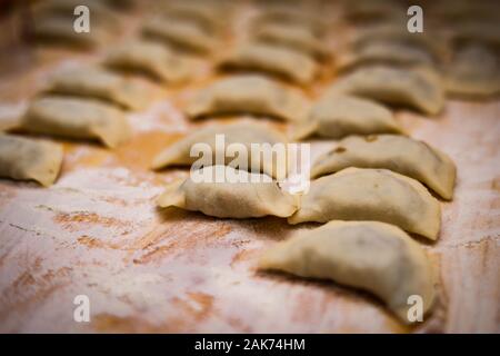 Pierogi. Knödel gestapelt nebeneinander auf einem Holzbrett Momente vor dem Kochen. Traditionelle Osteuropäische Weihnachten Teller. Stockfoto