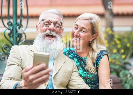 Gerne älteres Paar beobachten auf Smart Phone und gemeinsam lachen - reife Art und Weise Leute Spaß mit Neue Technologie Handy im Freien Stockfoto