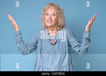 Senior kaukasische Frau wirft die Hände zuckte mit den Schultern unsicher, wobei einige Zweifel. Studio shot Stockfoto