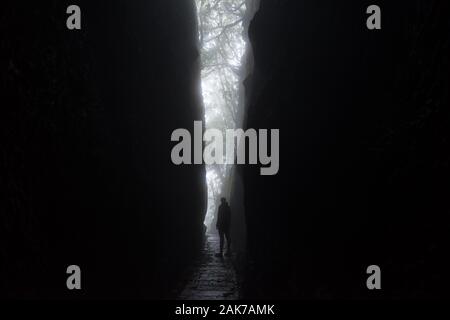 Silhouette eines großen unkenntlich Frau heraus, die von einer dramatischen Kluft in die Felsen der Berge auf der Insel Madeira. Das Licht bildet eine V-Form Stockfoto