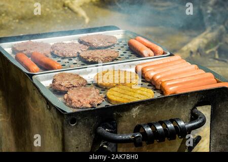 Horizontale Schuß von Hot Dogs und Burger vom Grill auf einen Grill im Freien. Stockfoto