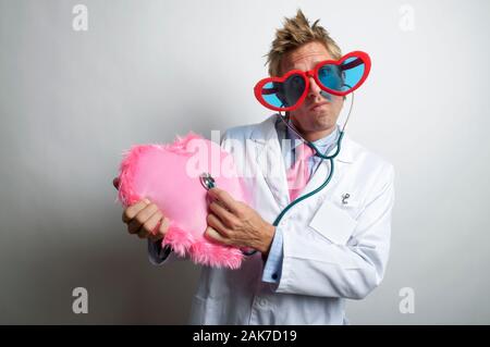 Liebe den Arzt mit einer roten Brille, die auf seinem Stethoskop einem großen pinkfarbenen, unscharfen Herzen lauscht Stockfoto