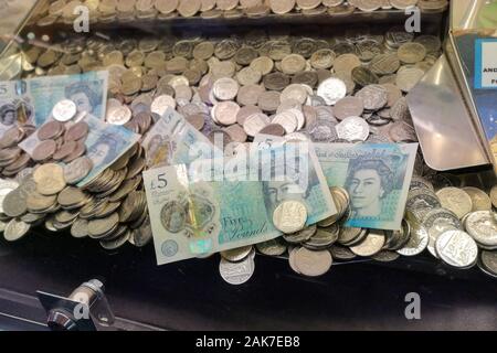 Geld ist in einer "Coin Pusher 'arcade spiel in Swanage, Dorset, November 2019 gesehen. Stockfoto