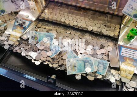 Geld ist in einer "Coin Pusher 'arcade spiel in Swanage, Dorset, November 2019 gesehen. Stockfoto