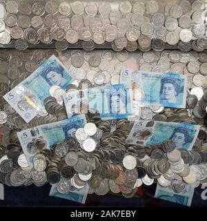 Geld ist in einer "Coin Pusher 'arcade spiel in Swanage, Dorset, November 2019 gesehen. Stockfoto