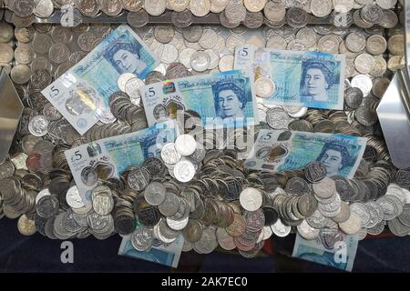 Geld ist in einer "Coin Pusher 'arcade spiel in Swanage, Dorset, November 2019 gesehen. Stockfoto