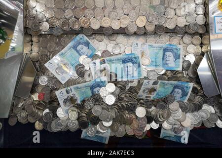 Geld ist in einer "Coin Pusher 'arcade spiel in Swanage, Dorset, November 2019 gesehen. Stockfoto