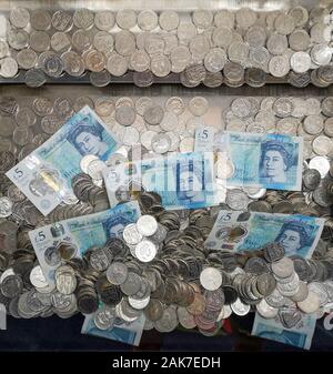 Geld ist in einer "Coin Pusher 'arcade spiel in Swanage, Dorset, November 2019 gesehen. Stockfoto