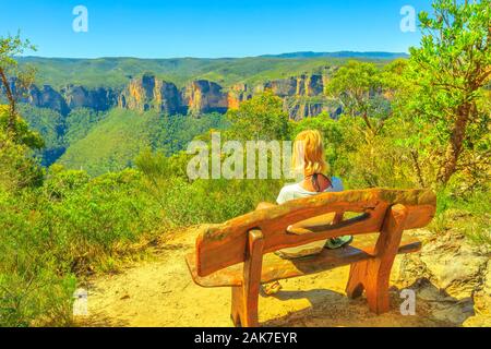 Kaukasische touristische Frau sitzt auf der Holzbank, suchen einen schönen Panoramablick, Anvil Rock Trail in der Nähe von Blackheath. Blue Mountains National Park, Neue Stockfoto