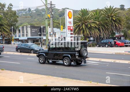 Land Rover Defender Black, der an einer Shell-Tankstelle in Sydney, New South Wales, Australien vorbeifährt Stockfoto
