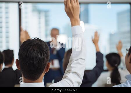 Die erhobenen Hände und Arme der großen Gruppe im Seminar class Zimmer zu vereinbaren Frage zum Lautsprecher an der Konferenz seminar Konferenzraum oder Stockfoto