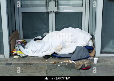 Person, die rauh unter der Decke in der Tür von Colchester, Essex, Großbritannien schläft Stockfoto