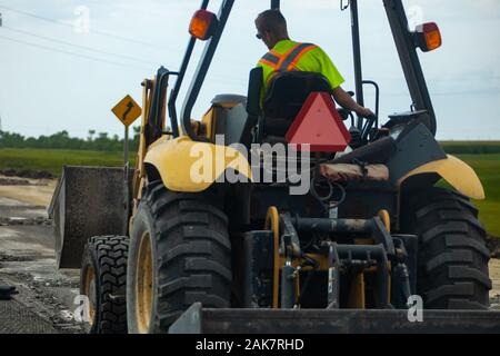 Eine Rückansicht eines großen Traktor mit Schaufel, als Lader oder Digger bekannt ausgestattet, bei der Arbeit die Nivellierung Boden in einer großen Farm Feld, mit Kopie Raum Stockfoto