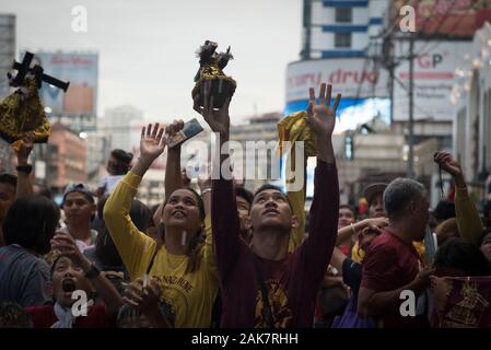 Ein Mann hebt eine Replik des Schwarzen Nazareners Skulptur während der Parade. Tausende von Römisch-katholischen Gläubigen in einer Parade vor dem Fest des Schwarzen Nazareners in Manila, Philippinen. Millionen wird erwartet, dass der Höhepunkt des Festes am 9. Januar, wo die katholischen Gläubigen vie wird eine lebensgroße Skulptur eines dunkelhäutigen Jesus Christus - die schwarzen Nazareners - zu berühren, da es durch die Straßen von Manila marschierten zu verbinden. Auf den Philippinen ist eine von nur zwei katholischen Mehrheit Länder in Südostasien, neben Osttimor. Stockfoto