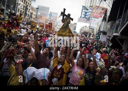 Ein Mann hebt eine Replik des Schwarzen Nazareners Skulptur während der Parade. Tausende von Römisch-katholischen Gläubigen in einer Parade vor dem Fest des Schwarzen Nazareners in Manila, Philippinen. Millionen wird erwartet, dass der Höhepunkt des Festes am 9. Januar, wo die katholischen Gläubigen vie wird eine lebensgroße Skulptur eines dunkelhäutigen Jesus Christus - die schwarzen Nazareners - zu berühren, da es durch die Straßen von Manila marschierten zu verbinden. Auf den Philippinen ist eine von nur zwei katholischen Mehrheit Länder in Südostasien, neben Osttimor. Stockfoto