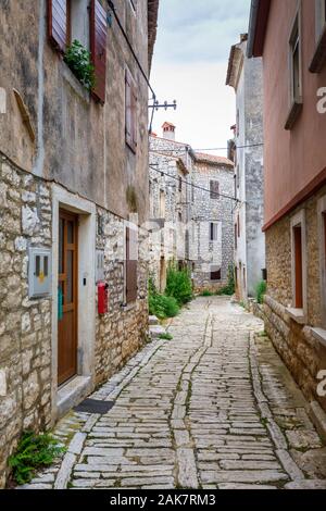 Eine gepflasterte Gasse zwischen alten Gebäuden in der historischen Altstadt in Ballen, einer kleinen Stadt auf dem Mont Perin in der Gespanschaft Istrien, Kroatien Stockfoto