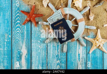 Kapitän Lenkrad Travel Concept mit Geld-Scheine auf Sand Sterne Fischen und Muscheln uns Pass auf alten blauen Holz- Hintergrund Stockfoto