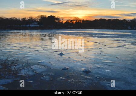 Ein winter Sonnenuntergang senkt sich über einen gefrorenen Hafen. Stockfoto