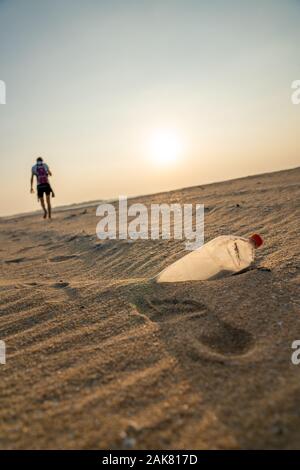 Person zu Fuß entfernt von Müll am Strand Stockfoto