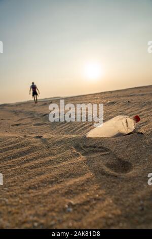 Person zu Fuß entfernt von Müll am Strand Stockfoto