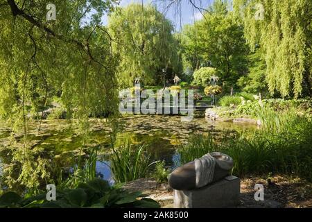 Teich und Brücke durch Äste im Frühling, Centre de la Nature, Saint-Vincent-de-Paul, Laval, Quebec, Kanada. Stockfoto