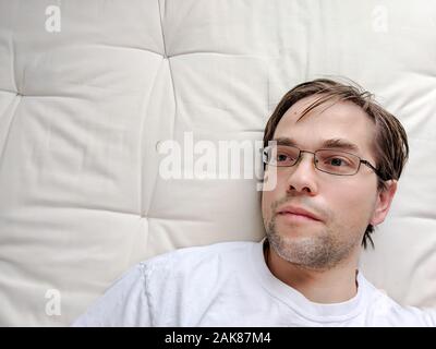 Junger Mann auf dem Bett liegend Stockfoto