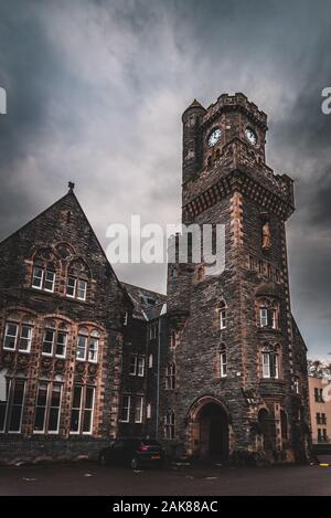 FORT AUGUSTUS, Schottland, 17. Dezember 2018: Die Abtei Highland Club Clock Tower, voller Schimmel und Flechten in seinen Steinmauern, unter starkem cloudscape Stockfoto