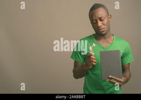 Junge afrikanische Mann, grünes T-Shirt gegen grauer Hintergrund Stockfoto