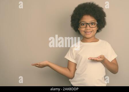 Junge niedlichen afrikanischen Mädchen gegen grauer Hintergrund Stockfoto