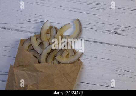 Natürliche getrocknete Kokosnuss im Papier auf einem hellen Hintergrund gewickelt. Coconut Chips Stockfoto